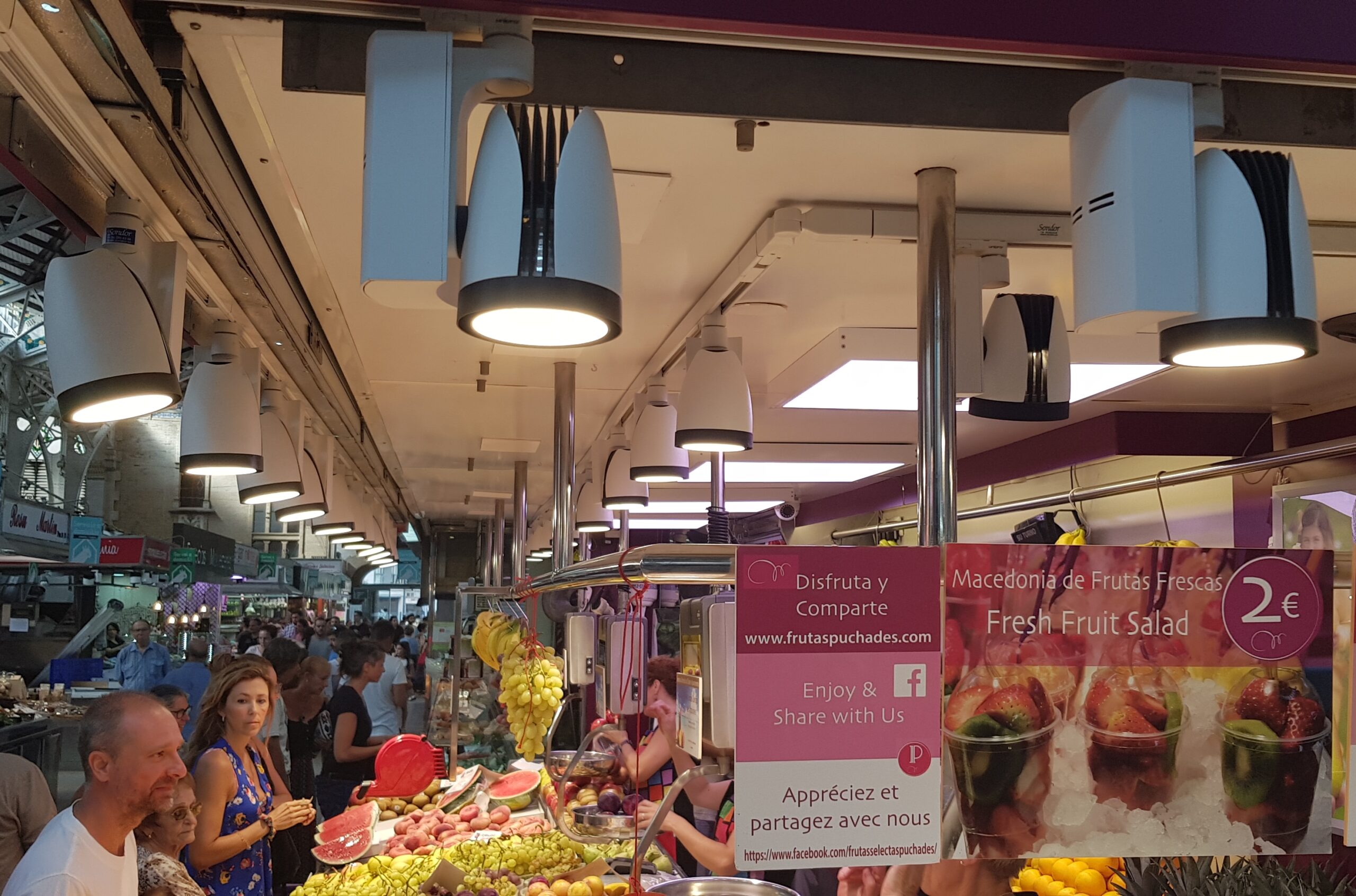 Mostrador de una frutería con productos iluminados y clientes